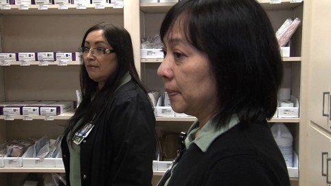 Two nurse examine supplies in their supply closet 